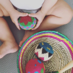 Montessori baby holding textured ball in basket
